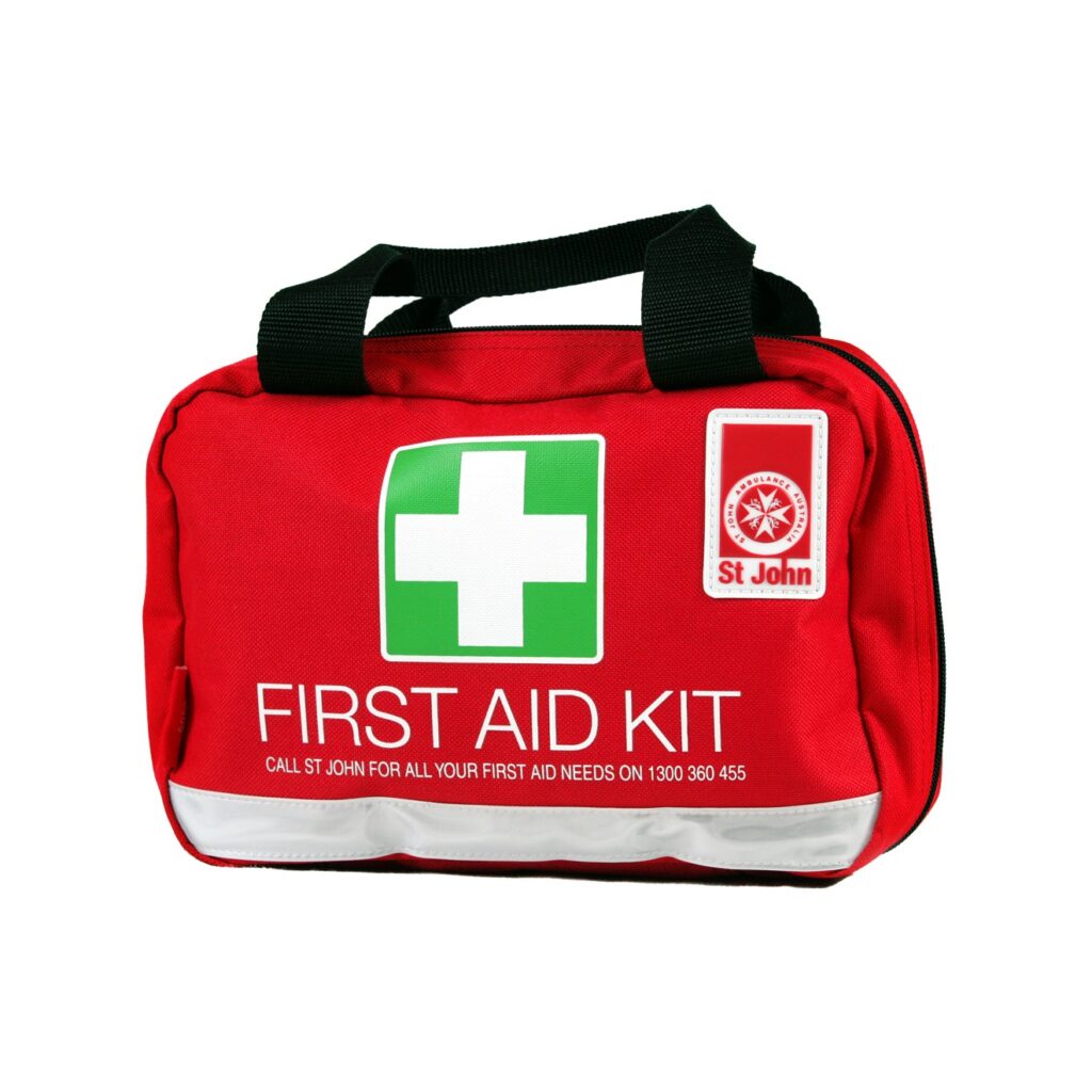 תיק עזרה ראשונה (First Aid Kit) אדום ובולט של ארגון St John, עם צלב לבן על רקע ירוק וידיות נשיאה שחורות, המיועד לטיולים ומצבי חירום.