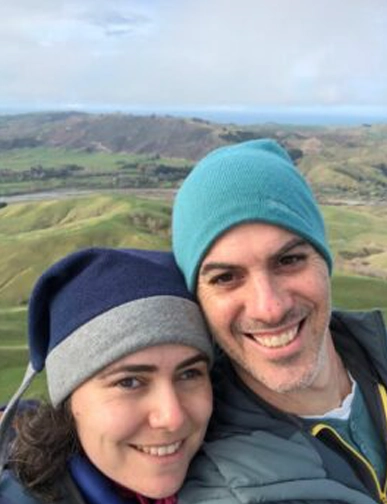 יפעת וגלעד מחייכים יחד על רקע גבעות ירוקות בניו זילנד