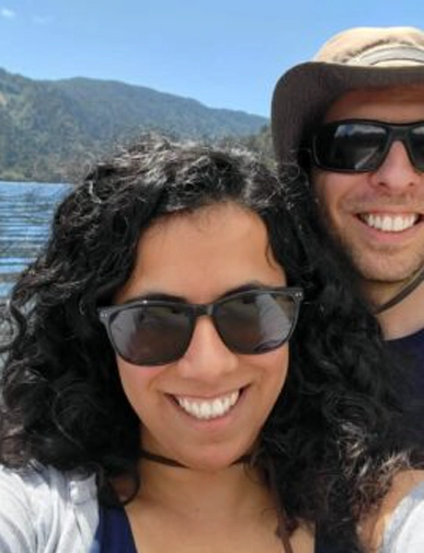 רונה ופיטר מחייכים יחד ליד אגם עם הרים ברקע